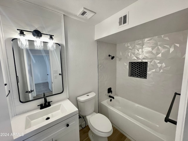 full bathroom featuring hardwood / wood-style floors, vanity, tiled shower / bath combo, toilet, and a textured ceiling