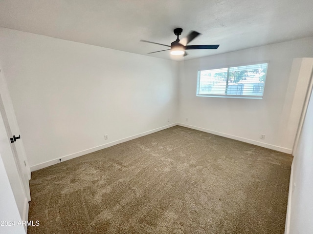 spare room with ceiling fan and dark carpet