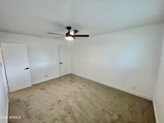 carpeted spare room featuring ceiling fan