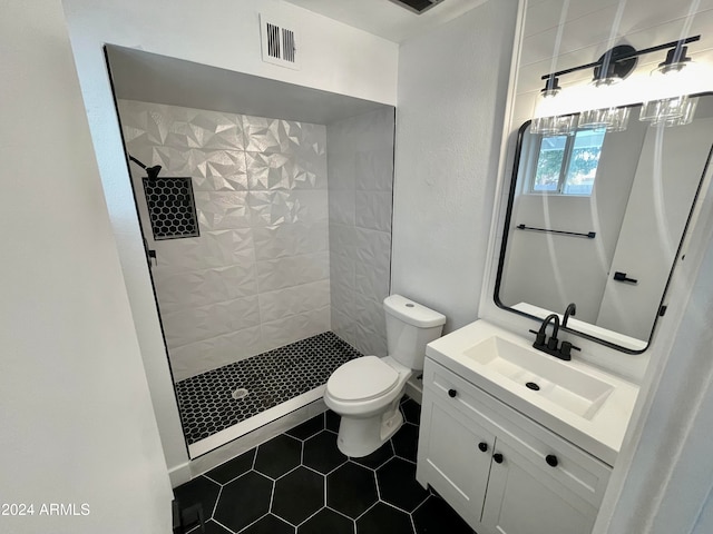 bathroom featuring toilet, a tile shower, vanity, and tile patterned floors