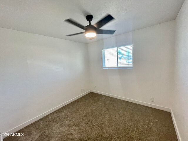 empty room featuring dark colored carpet and ceiling fan