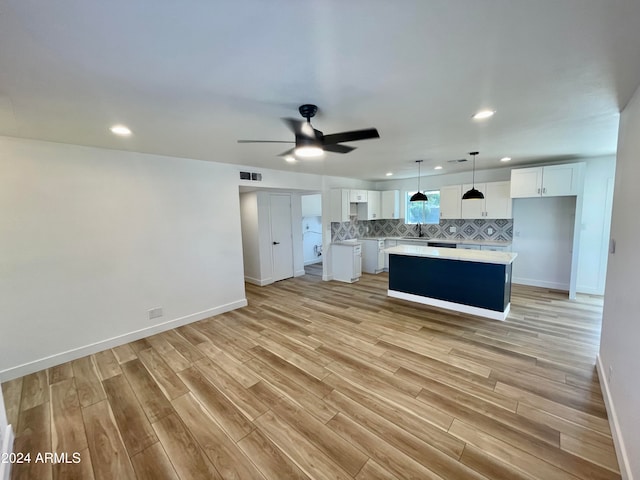 kitchen featuring white cabinets, decorative light fixtures, a center island, and light hardwood / wood-style floors