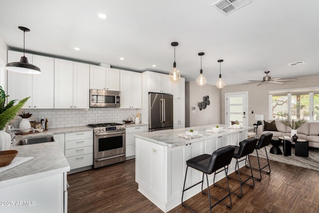 kitchen with a center island, open floor plan, visible vents, backsplash, and appliances with stainless steel finishes