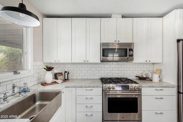 kitchen featuring white cabinets, decorative backsplash, stainless steel appliances, and a sink