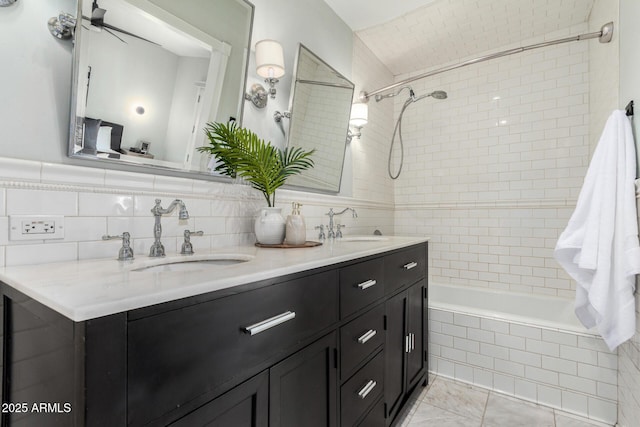 bathroom featuring tile walls, a sink, double vanity, and tiled shower / bath