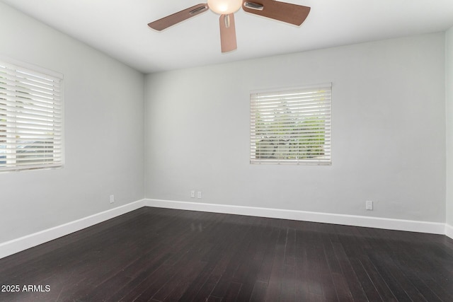 spare room featuring dark wood finished floors, a ceiling fan, and baseboards