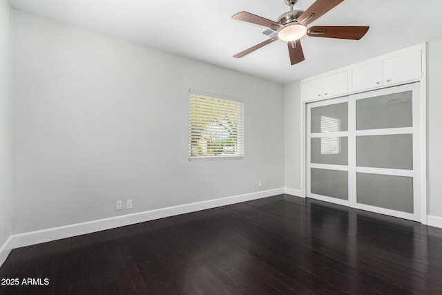 unfurnished room with baseboards, dark wood-style floors, and ceiling fan