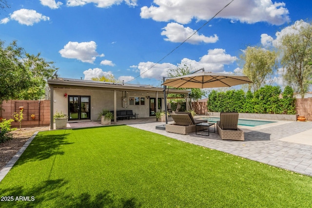 rear view of property featuring a lawn, french doors, a fenced backyard, a patio, and a fenced in pool