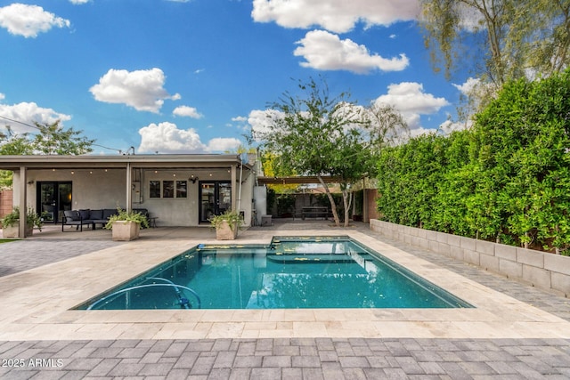view of pool with an outdoor living space, a patio area, french doors, a fenced backyard, and a fenced in pool