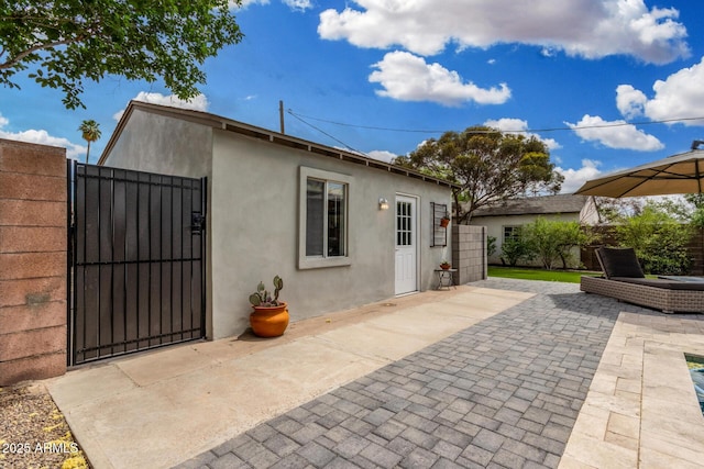 rear view of house featuring fence, a patio area, a gate, and stucco siding