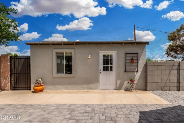 back of property featuring a gate, a patio area, stucco siding, and fence