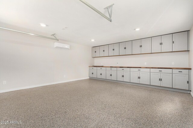 garage with baseboards, a wall mounted AC, and recessed lighting