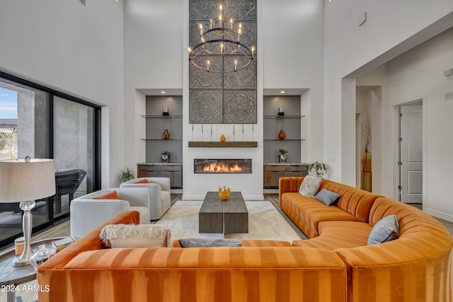 living room featuring a high ceiling, a chandelier, built in features, and a fireplace