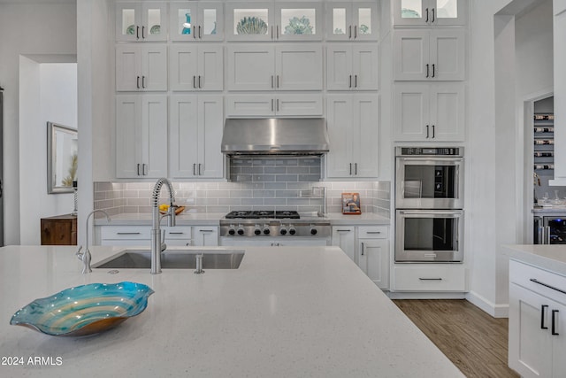 kitchen featuring appliances with stainless steel finishes, tasteful backsplash, white cabinetry, sink, and dark hardwood / wood-style flooring