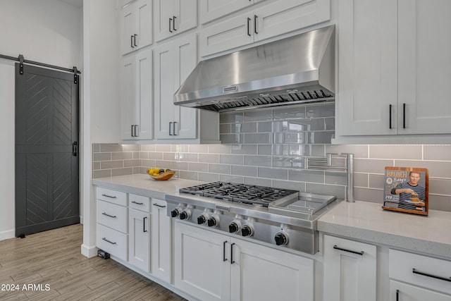 kitchen featuring light stone counters, stainless steel gas stovetop, light hardwood / wood-style flooring, and white cabinets