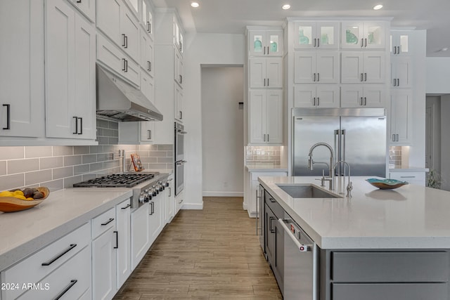 kitchen featuring sink, light wood-type flooring, appliances with stainless steel finishes, an island with sink, and white cabinets