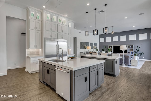 kitchen with an island with sink, sink, gray cabinetry, white cabinets, and stainless steel appliances