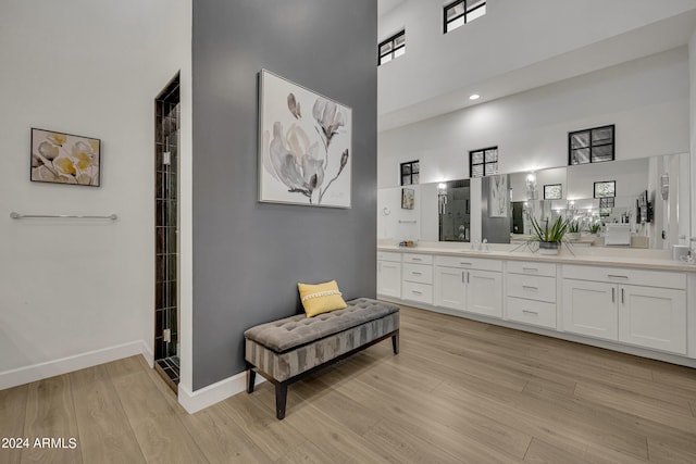 bathroom with vanity, hardwood / wood-style flooring, a shower, and a high ceiling