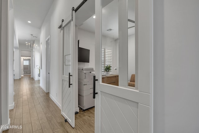 hall with a barn door and light hardwood / wood-style flooring