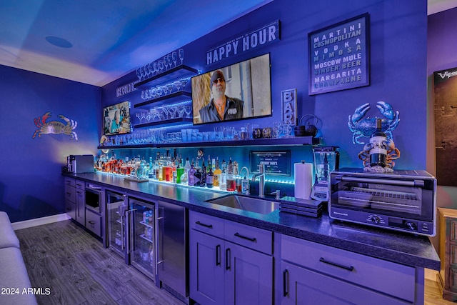 bar featuring stainless steel microwave, sink, and wood-type flooring