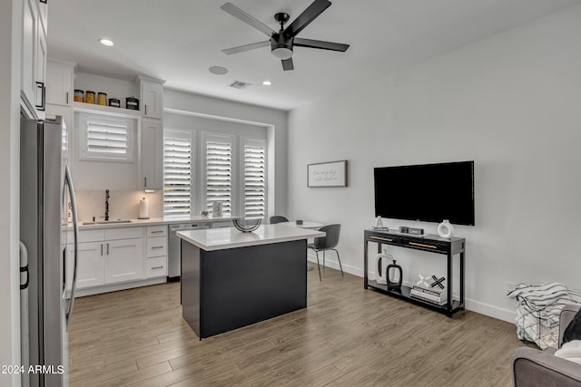 kitchen with sink, light hardwood / wood-style flooring, appliances with stainless steel finishes, white cabinetry, and a kitchen island