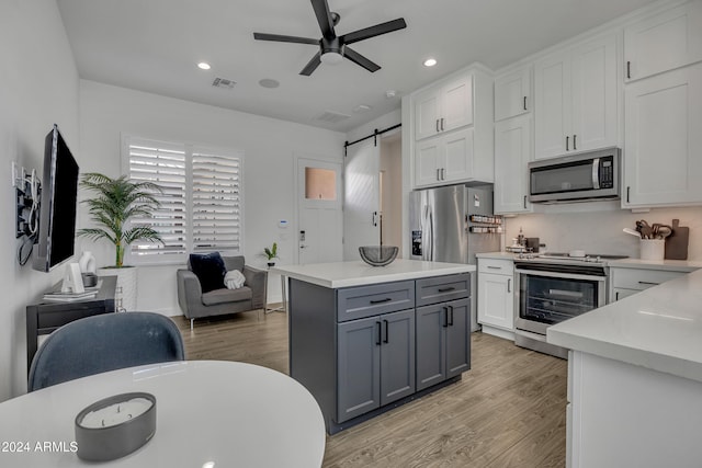 kitchen featuring light hardwood / wood-style flooring, appliances with stainless steel finishes, gray cabinetry, white cabinets, and a barn door