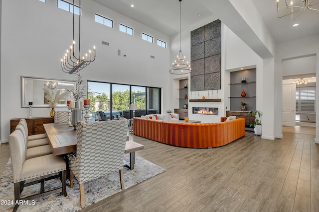 dining area featuring a large fireplace, a chandelier, light hardwood / wood-style floors, and built in shelves