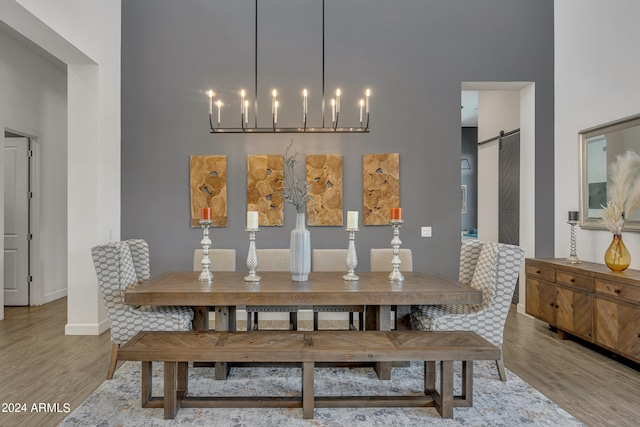 dining area with a towering ceiling, a barn door, and hardwood / wood-style floors