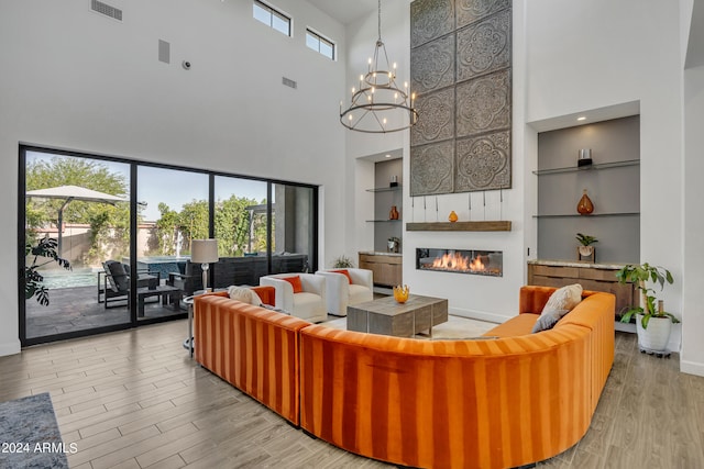 living room featuring a chandelier, light wood-type flooring, and built in shelves