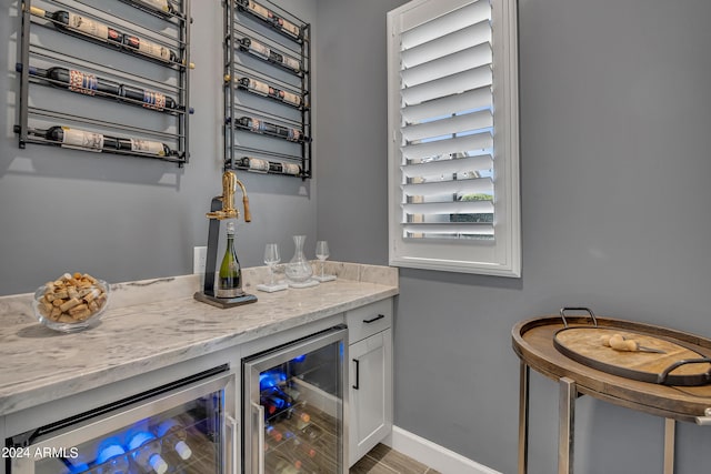 bar featuring white cabinets, light stone countertops, and beverage cooler