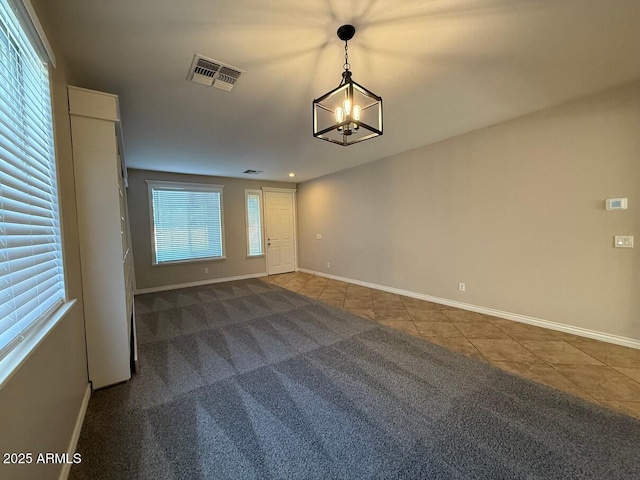 tiled spare room featuring an inviting chandelier