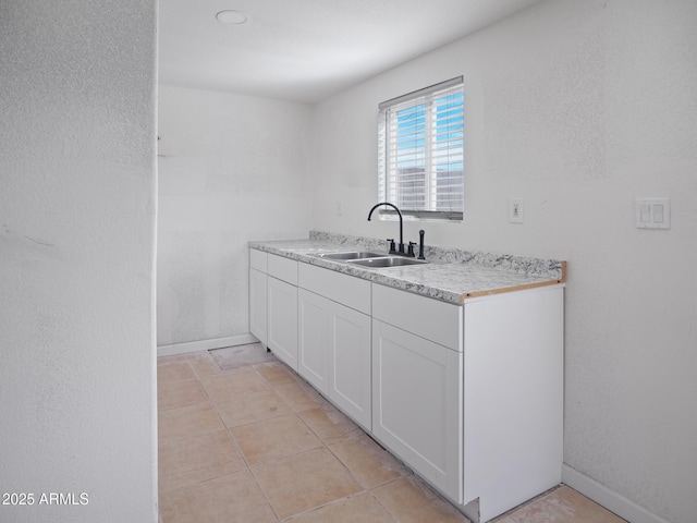 kitchen with white cabinetry, sink, and light tile patterned floors