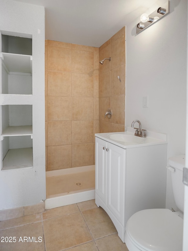 bathroom with tile patterned flooring, vanity, a tile shower, and toilet