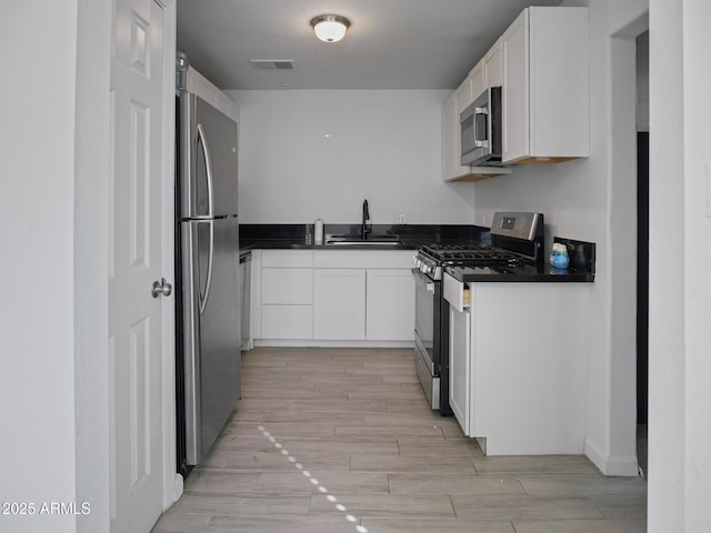 kitchen with stainless steel appliances, white cabinetry, and sink