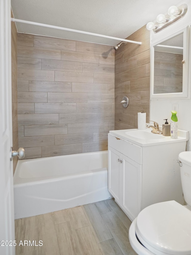 full bathroom with vanity, tiled shower / bath combo, a textured ceiling, and toilet