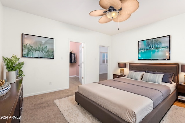 bedroom with light carpet, a closet, a walk in closet, and ceiling fan