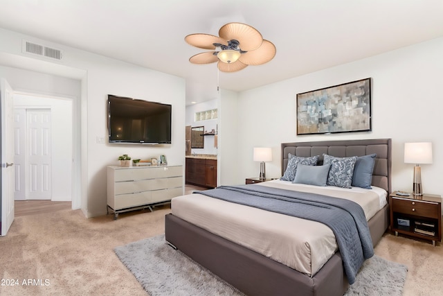 bedroom with light carpet, ceiling fan, and connected bathroom