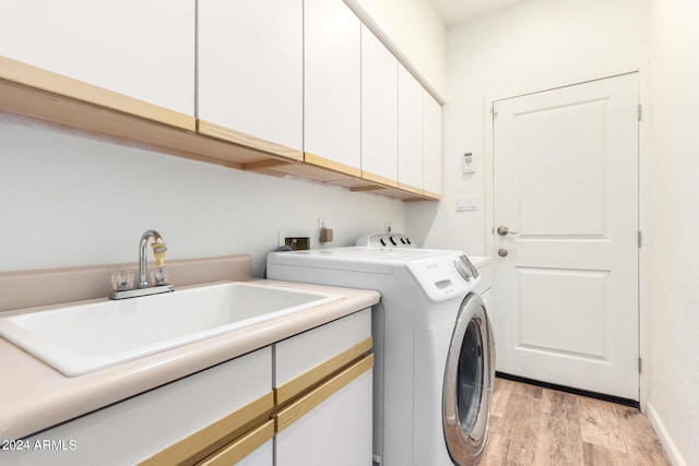 washroom with cabinets, sink, light hardwood / wood-style floors, and washing machine and dryer