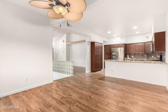 kitchen featuring decorative backsplash, light stone countertops, light hardwood / wood-style floors, and appliances with stainless steel finishes