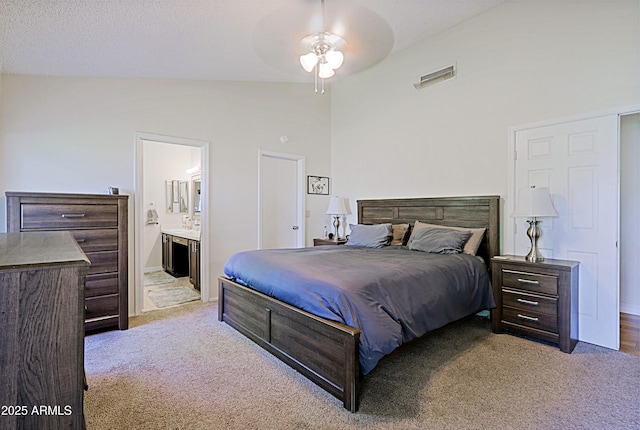 bedroom with lofted ceiling, carpet floors, ensuite bath, and visible vents