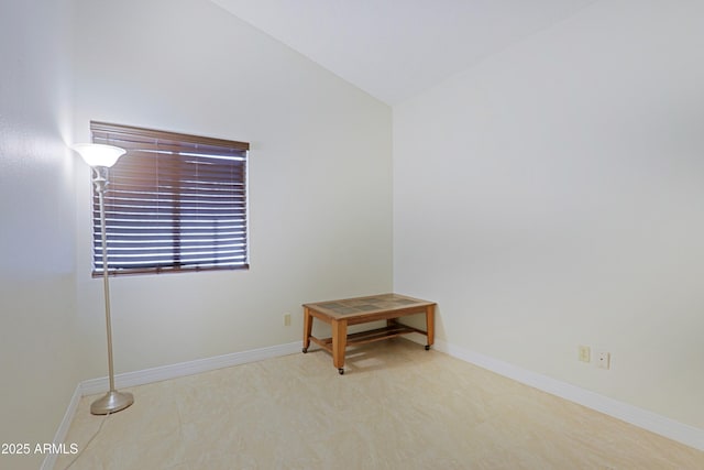 unfurnished room featuring lofted ceiling and baseboards