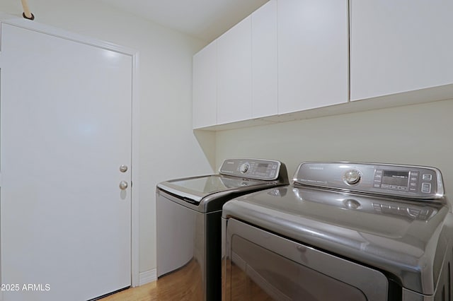 laundry area featuring light wood finished floors, cabinet space, and washer and dryer