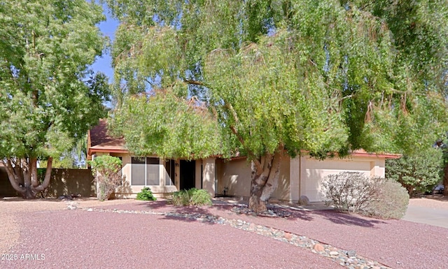 obstructed view of property featuring an attached garage, driveway, and stucco siding