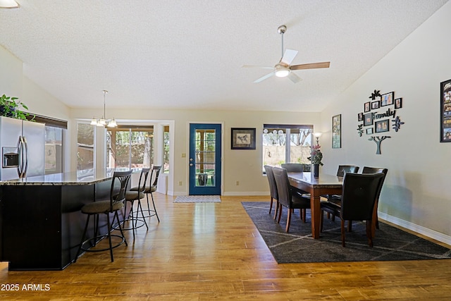 dining area featuring a healthy amount of sunlight, light wood-type flooring, and vaulted ceiling