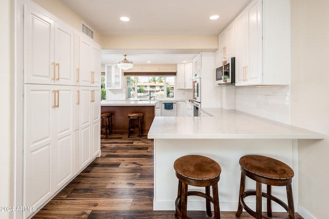 kitchen featuring white cabinets, kitchen peninsula, and a breakfast bar area