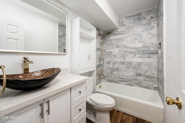 full bathroom featuring hardwood / wood-style floors, tiled shower / bath, vanity, and toilet