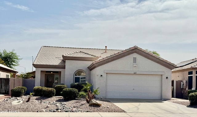 view of front facade with stucco siding, an attached garage, fence, driveway, and a tiled roof