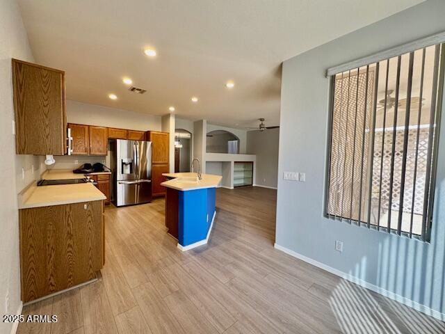 kitchen with a sink, visible vents, light countertops, brown cabinets, and stainless steel fridge