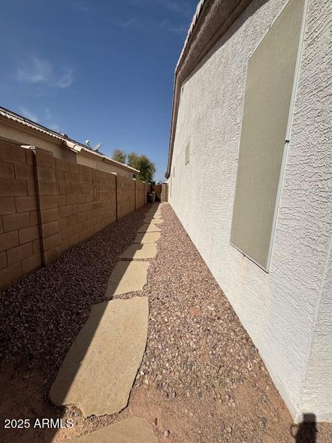 view of side of home with a fenced backyard and stucco siding