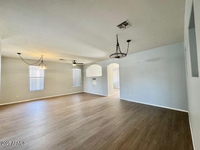 interior space featuring dark wood-style floors, ceiling fan, visible vents, and arched walkways